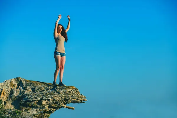 Acrophobia tall woman stands on top of a rock cliff edge and is