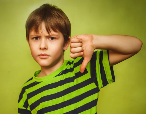 Boy teenager baby showing thumbs down on the big green backgroun