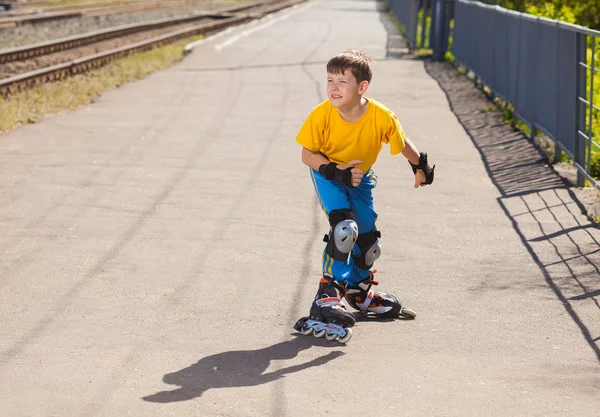 Teenager boy on roller skates in summer on asphalt street