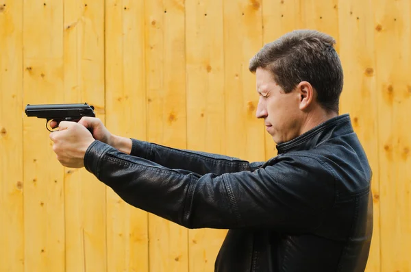 The man shoots from a pistol, having closed eyes