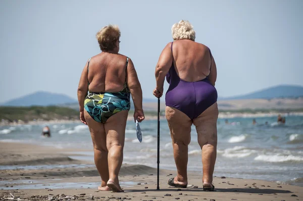 Elderly and fat old ladies walk on the beach