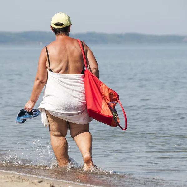 Elderly and fat old ladie walk on the beach