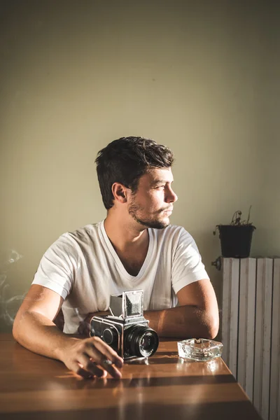 Young stylish hipster man with old camera