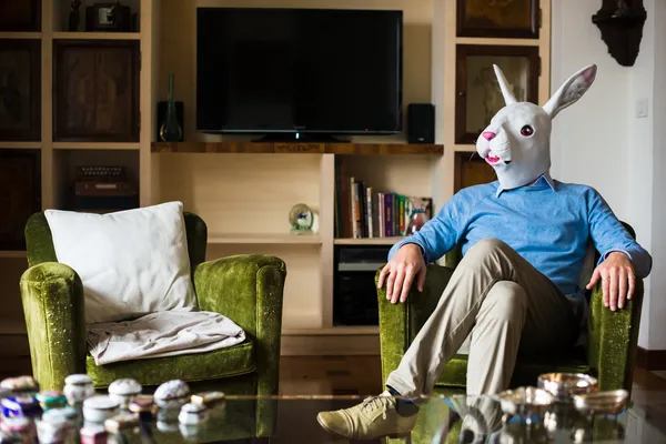 Elegant business multitasking rabbit mask man at home