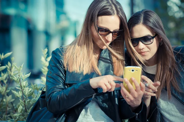 Two beautiful young women using smart phone