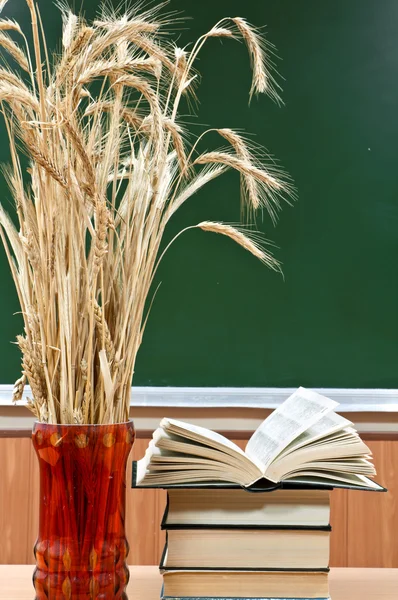 Books and vase with the ears of wheat on a background a school b