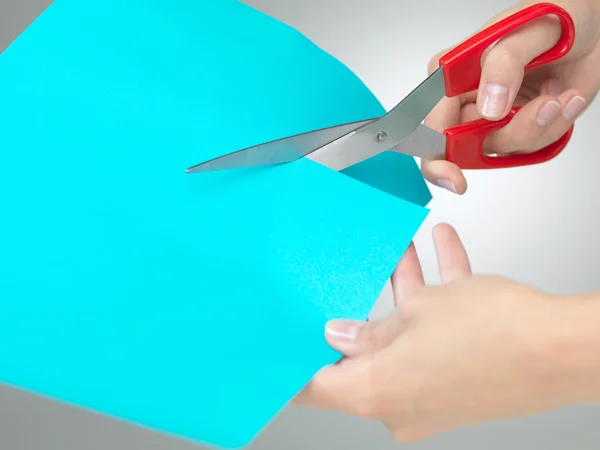 Hands cutting a paper with scissors