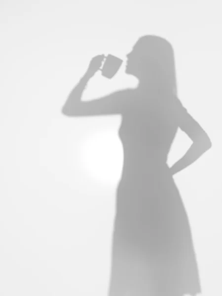 Woman drinking coffee from a mug, silhouette