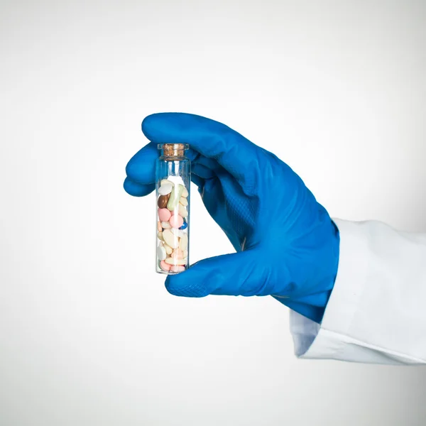 Pills in transparent bottle held by someone