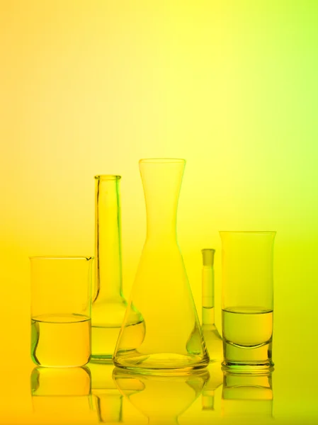 Laboratory glass recipients on yellow background