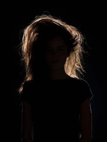 Woman with tousled hair in black shadow