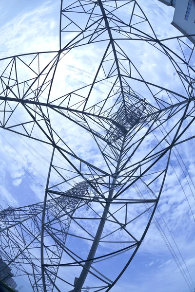 Look up high-voltage power tower in sun sky