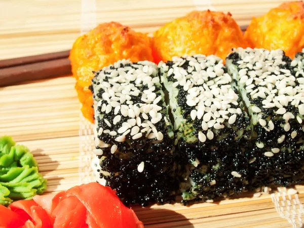 Rolls with black roe and sesame and baking sushi on bamboo mat