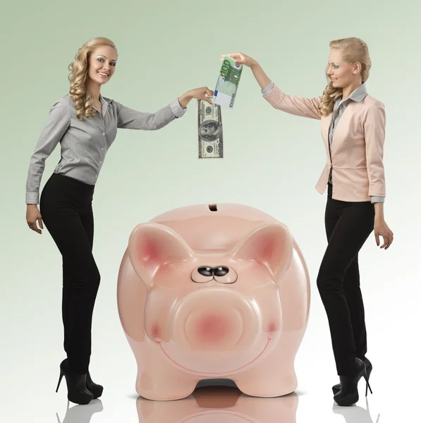 Two smiling girl saving their money euro dollar