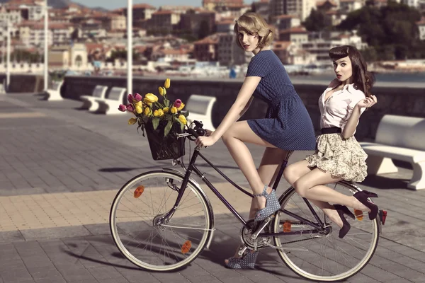 Two vintage women on bicycle near the sea