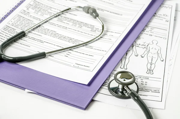 Stethoscope resting on a sheet of medical lab test results, with patient file and x-ray or mri film