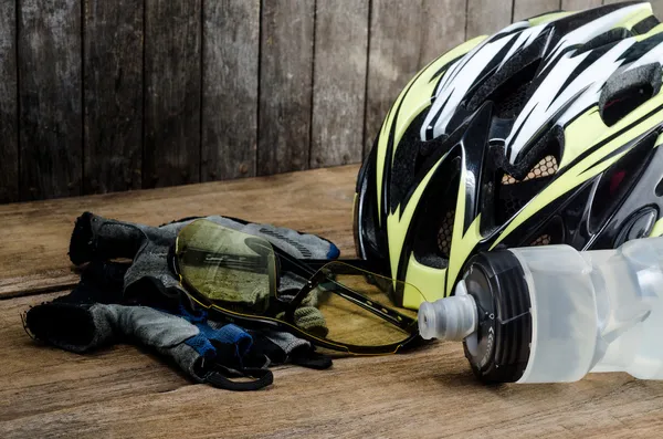 Helmet, gloves and water bottle - bicycle accessories on Wood table