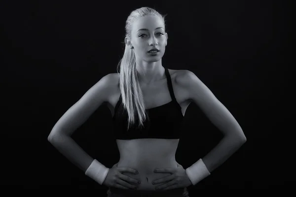 Black and white image of female athlete posing against black bac
