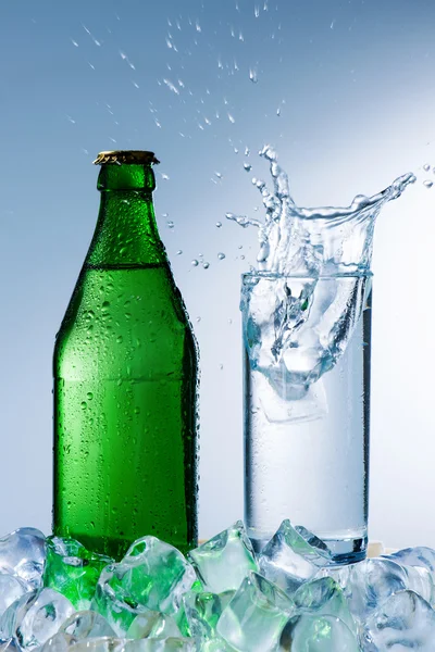 Bottle of mineral water with ice and a glass with water splash