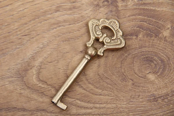 Ancient key with ornament on wooden background