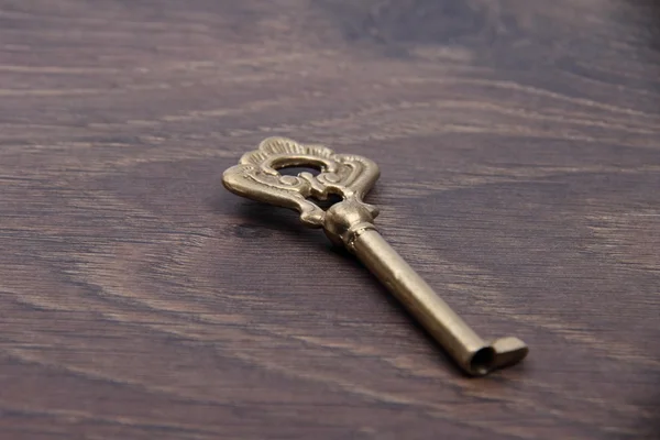 Ancient key with ornament on dark wooden background