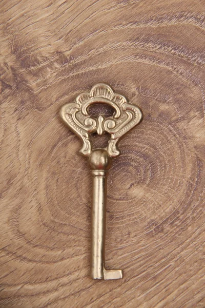 Ancient key with ornament isolated on wooden background