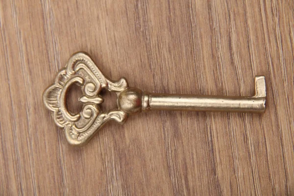 Ancient key with ornament isolated on wooden background