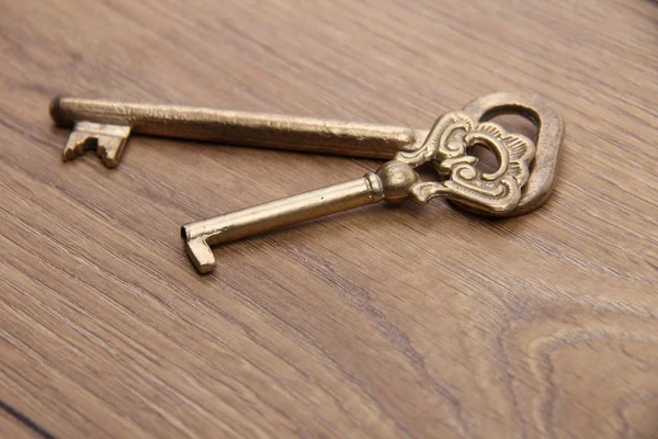 Two ancient keys with ornament on wooden background