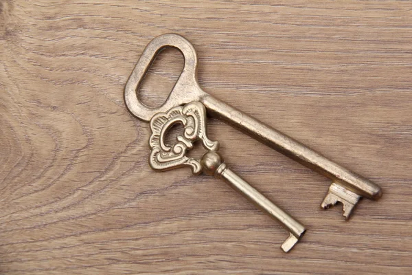 Two ancient metal keys with ornament on wooden background