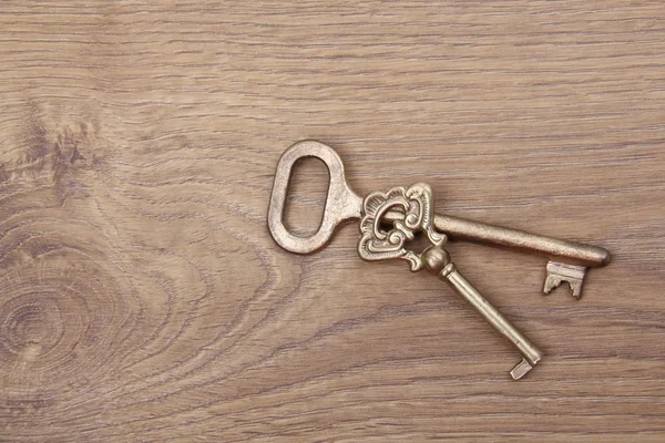 Two old keys with ornament on wooden background
