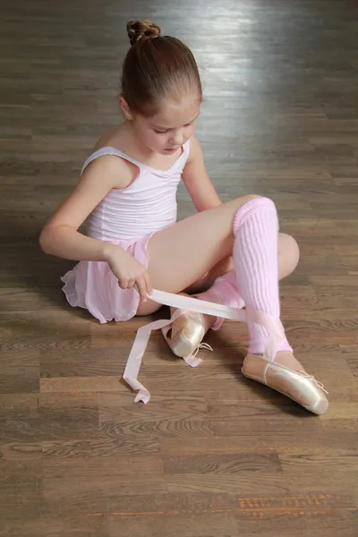 Smiling ballerina in a tutu and pointe posing for the camera in a ballet class