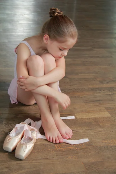 Young girl engaged in a pink ballet tutu and pointe in the ballet hall on the wooden dance floor