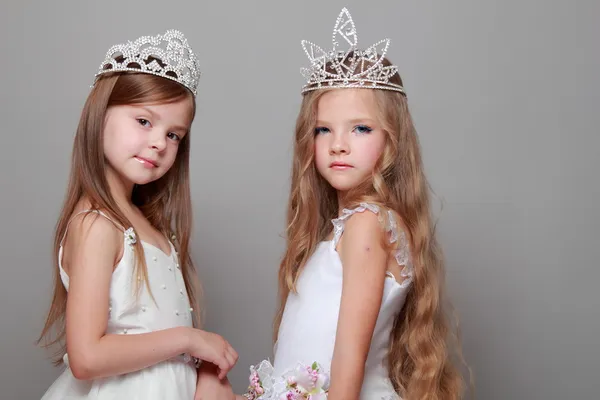 Smiling cute little girls in white dresses and a crown for the beauty contest