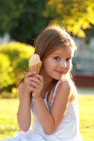 Smiling child eating ice-cream in summer park.