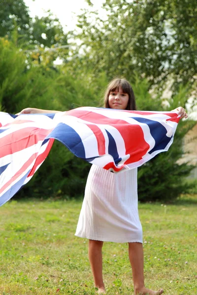 Cute girl holding a big Britain flag