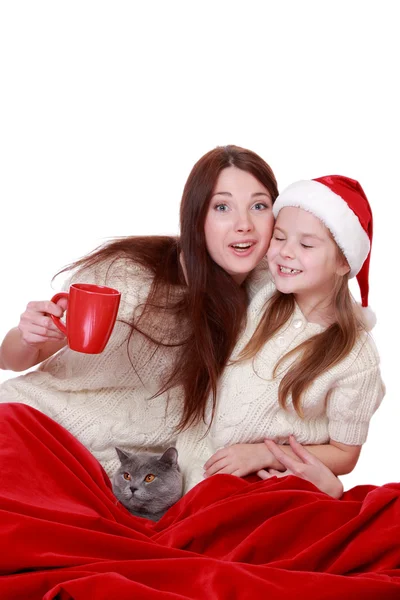 Mother and daughter holding cat over Christmas tree