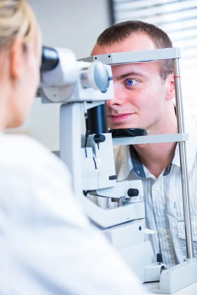 Optometry concept - handsome young man having her eyes examined