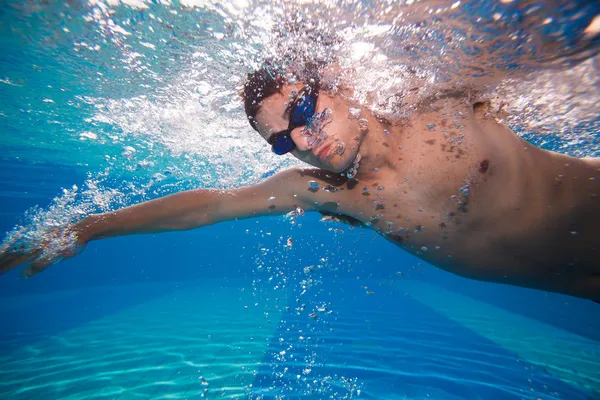 Young man swimming the front crawl in a pool - underwater shot (