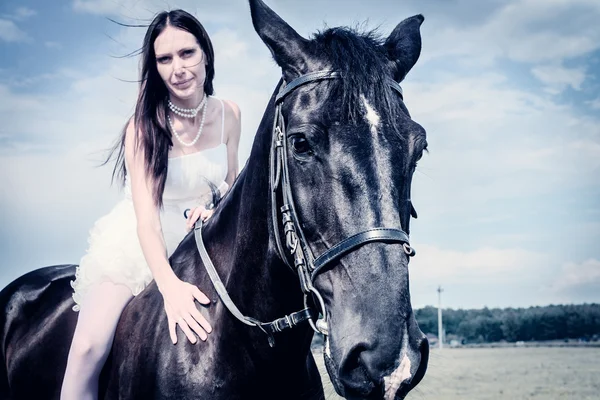 Unusual bride at wedding on black horse outdoors