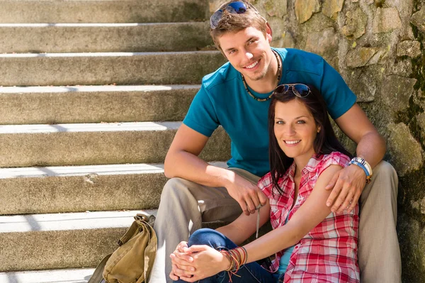 Happy young couple sitting on stairs smiling