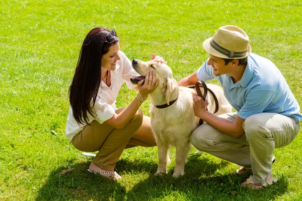 Young happy couple playing with Labrador dog