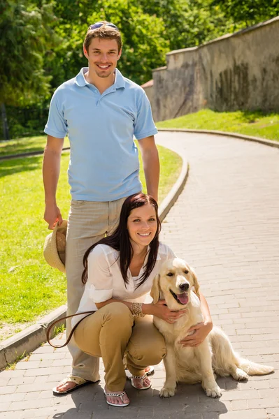 Happy couple with dog on park alley