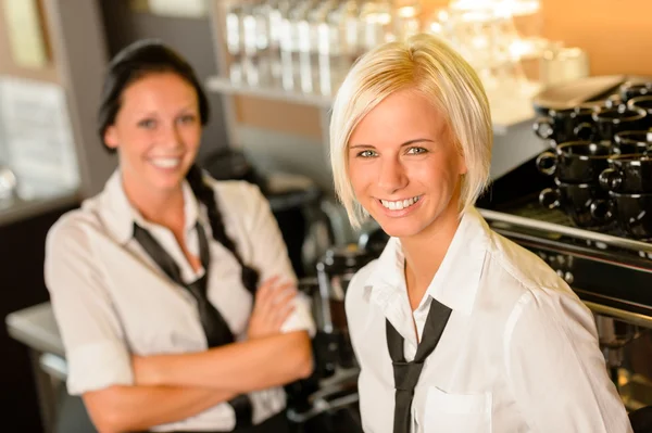 Cafe waitresses behind bar smiling at work