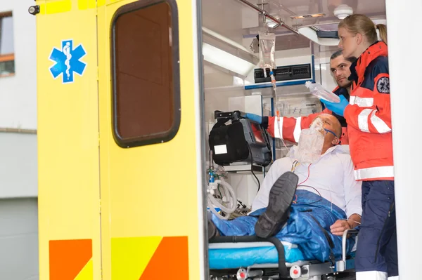 Paramedics checking IV drip patient in ambulance