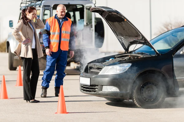 Woman with technician help smoking car engine