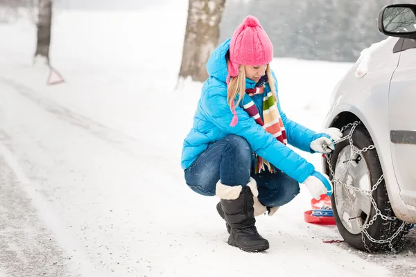 Woman putting winter tire chains car wheel