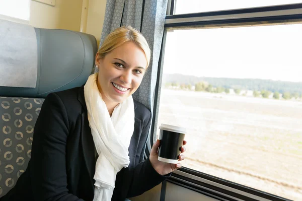 Woman smiling sitting in train holding coffee