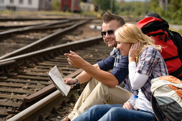 Man pointing direction with map on railroad