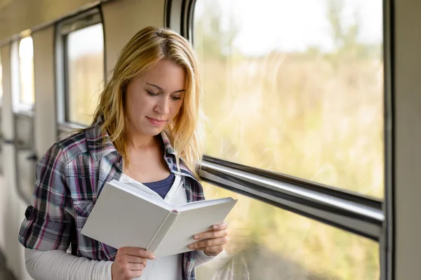 Woman reading a book by train window