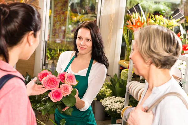 Happy florist woman showing roses flowers customers